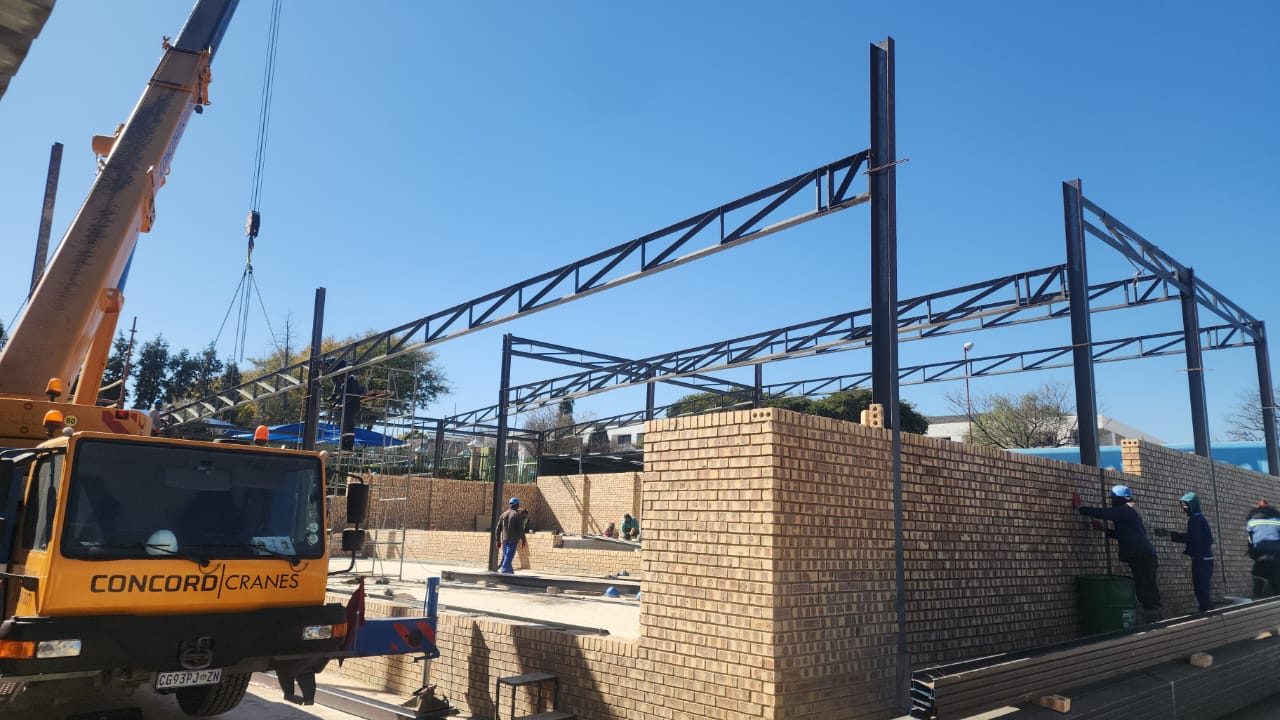 Steel roof trusses being erected by crane